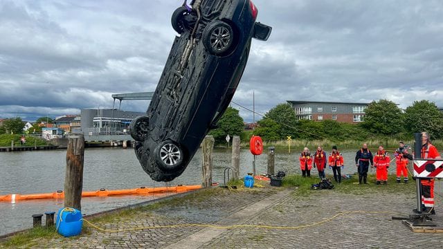 Einsatzkräfte ziehen mit einem Kran ein Auto aus dem Husumer Hafenbecken.