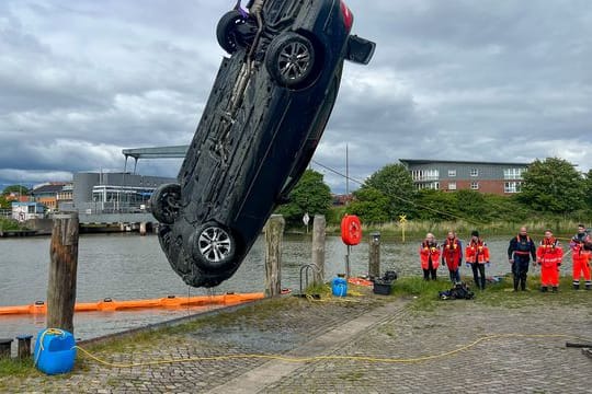 Einsatzkräfte ziehen mit einem Kran ein Auto aus dem Husumer Hafenbecken.