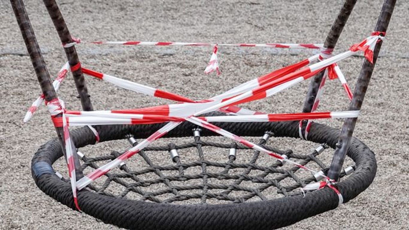 Eine Nestschaukel auf einem gesperrten Spielplatz im Leipziger Rosenthal ist mit rot-weißem Flatterband umwickelt.