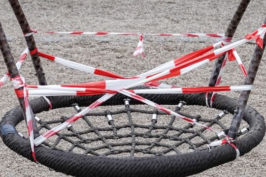 Eine Nestschaukel auf einem gesperrten Spielplatz im Leipziger Rosenthal ist mit rot-weißem Flatterband umwickelt.