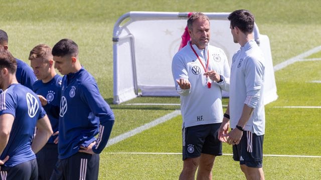 Trainer Hansi Flick (M) steht mit seinem Assistenten Danny Röhl (r) beim Training auf dem Platz.