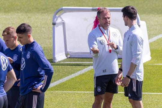 Trainer Hansi Flick (M) steht mit seinem Assistenten Danny Röhl (r) beim Training auf dem Platz.