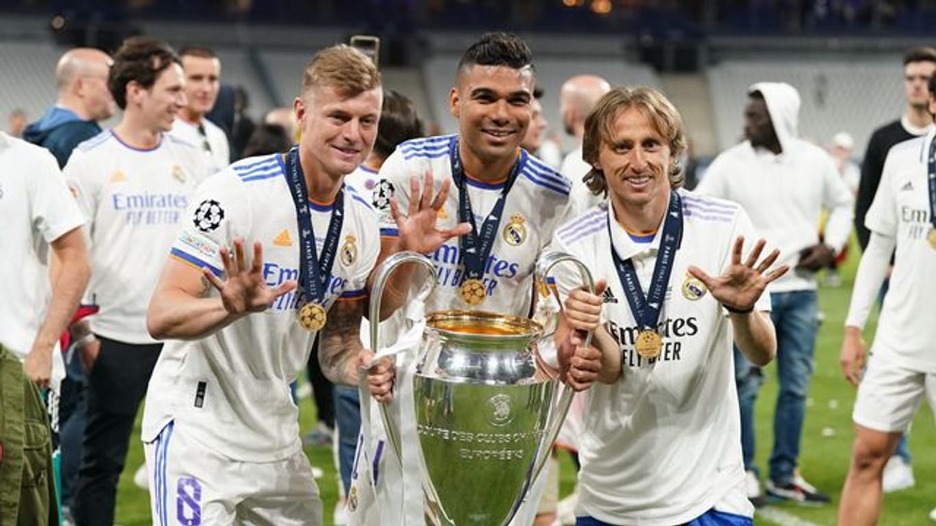 Toni Kroos (vorne, l-r), Carlos Casemiro und Luka Modric von Real Madrid jubeln mit der Trophäe nach dem Sieg der Champions League.