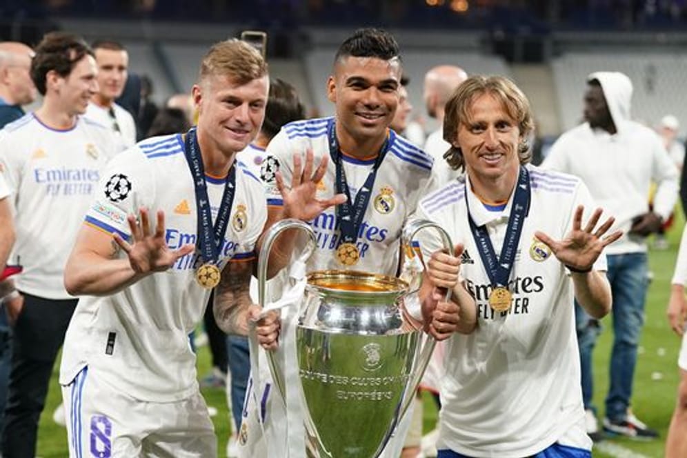 Toni Kroos (vorne, l-r), Carlos Casemiro und Luka Modric von Real Madrid jubeln mit der Trophäe nach dem Sieg der Champions League.