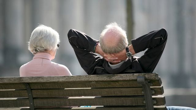 Senioren sitzen auf einer Bank in Berlin und genießen die Sonne.