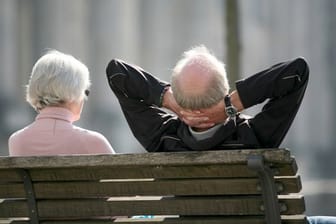 Senioren sitzen auf einer Bank in Berlin und genießen die Sonne.