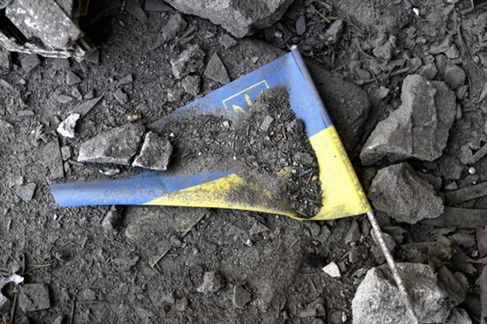 Eine ukrainische Flagge liegt nach einem Raketeneinschlag in Charkiw in den Trümmern.
