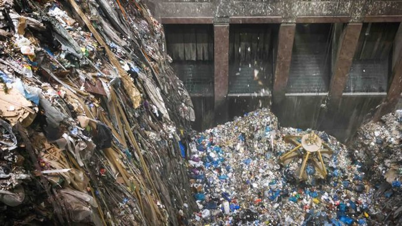 Mit einem großen Greifer sortiert und lockert ein Kran den angelieferten Abfall im Müllbunker einer Müllverwertungsanlage.