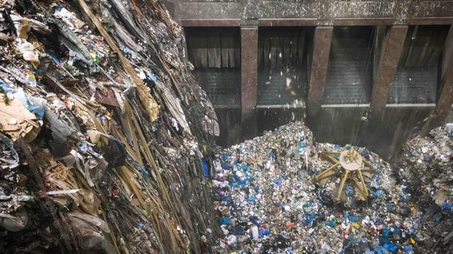 Mit einem großen Greifer sortiert und lockert ein Kran den angelieferten Abfall im Müllbunker einer Müllverwertungsanlage. Mit einem großen Greifer sortiert und lockert ein Kran den angelieferten Abfall im Müllbunker einer Müllverwertungsanlage.