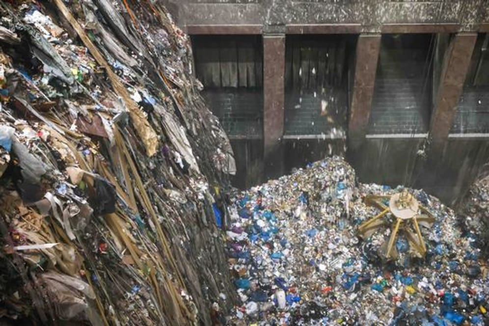 Mit einem großen Greifer sortiert und lockert ein Kran den angelieferten Abfall im Müllbunker einer Müllverwertungsanlage.
