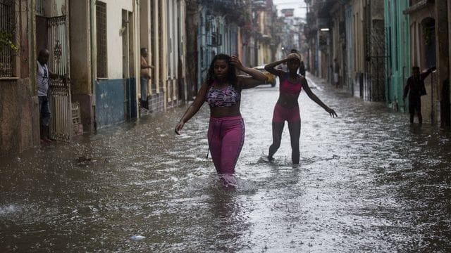 Zwei Frauen waten durch Hochwasser in Kubas Hauptstadt Havanna.