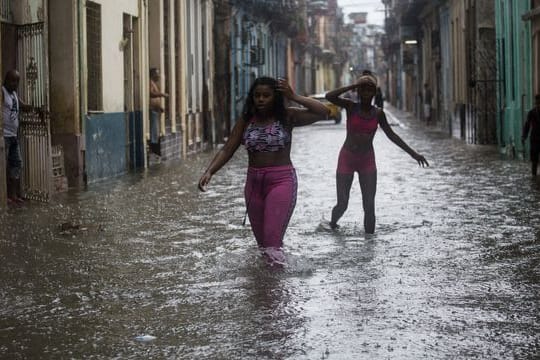 Zwei Frauen waten durch Hochwasser in Kubas Hauptstadt Havanna.