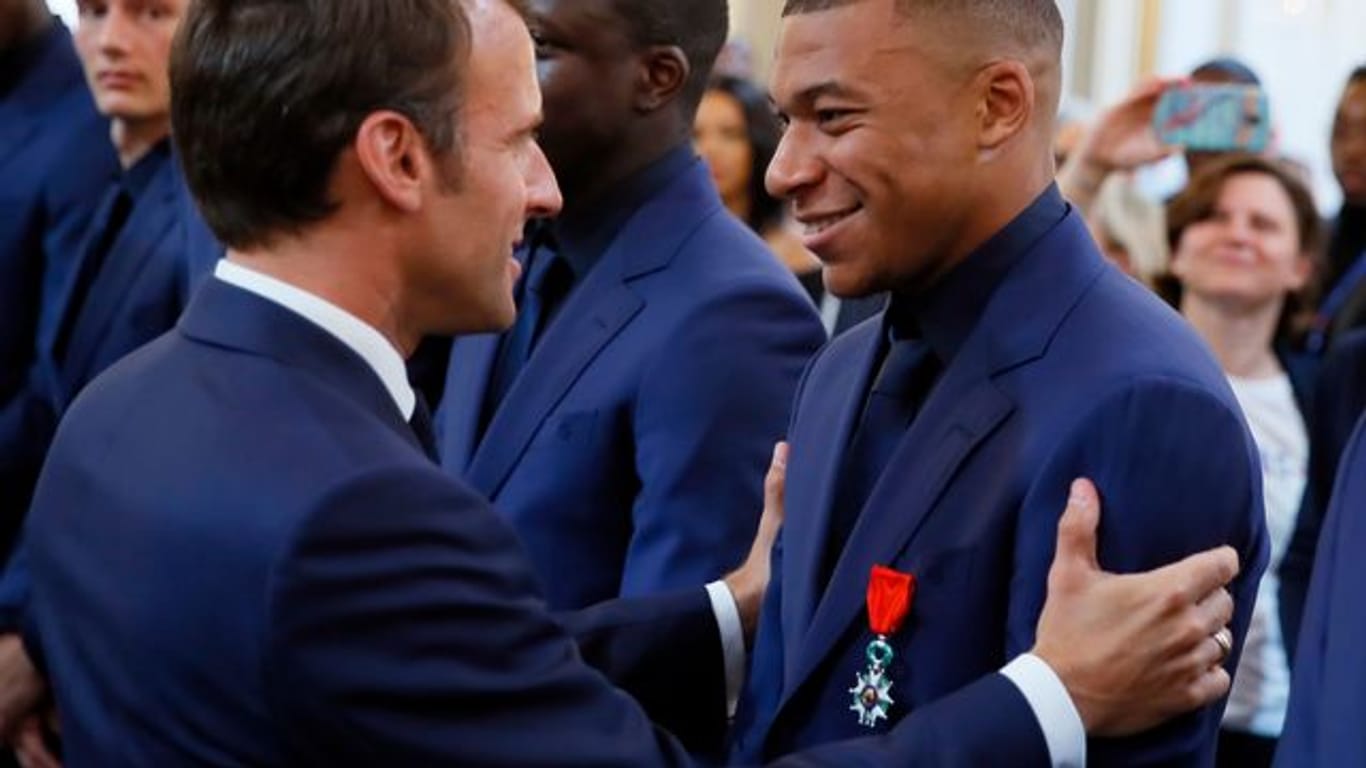 Frankreichs Präsident Emmanuel Macron (l) spricht bei einer Ehrung der Weltmeister von 2018 mit Kylian Mbappe.