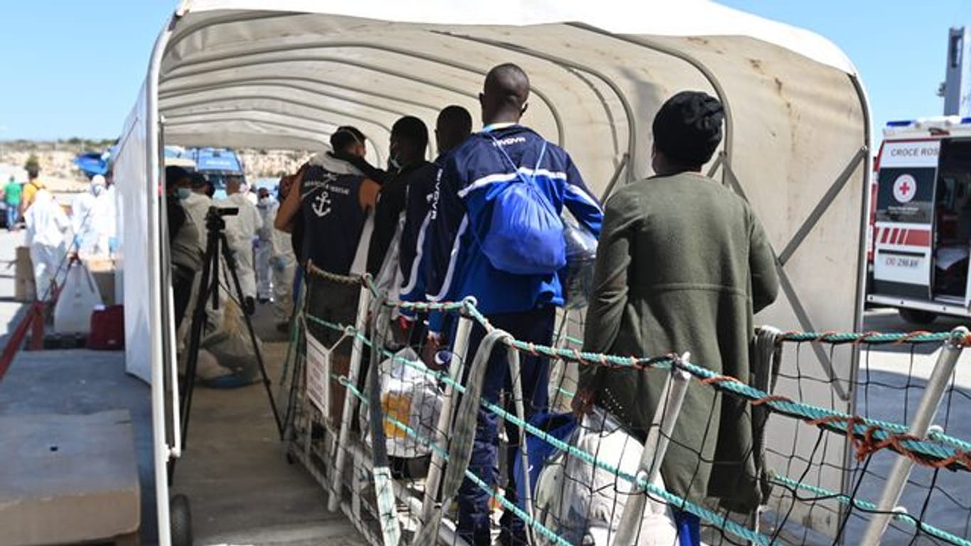 Menschen verlassen über eine Gangway das Rettungsschiff OceanViking der Hilfsorganisation SOS Mediterranee in Pozzallo, Sizilien.