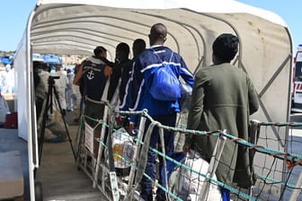 Menschen verlassen über eine Gangway das Rettungsschiff OceanViking der Hilfsorganisation SOS Mediterranee in Pozzallo, Sizilien.