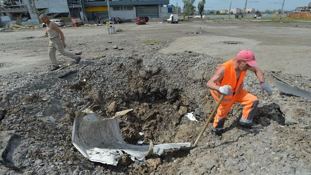 Ein Arbeiter beseitigt in Charkiw Rückstände aus einem Granatenkrater.