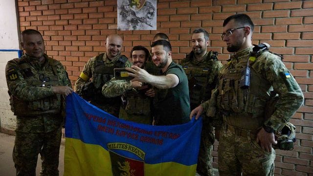 Der ukrainische Präsident Wolodymyr Selenskyj (M) besucht Soldaten an der Front.