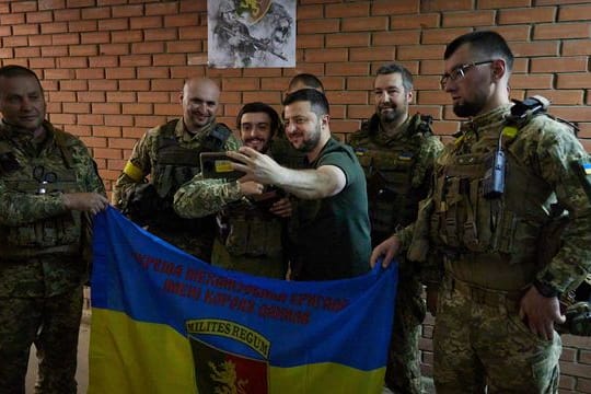 Der ukrainische Präsident Wolodymyr Selenskyj (M) besucht Soldaten an der Front.