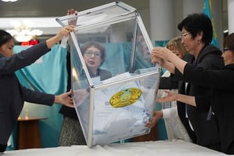 Mitglieder einer Wahlkommission entleeren die Stimmzettel aus einer Kiste.