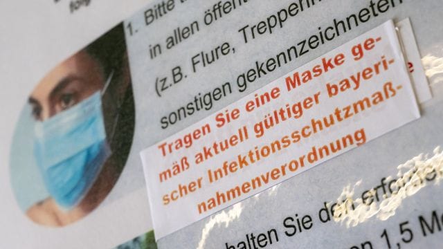 Ein Aufkleber mit der Aufschrift „Tragen Sie eine Maske gemäß aktuell gültiger bayerischer Infektionsschutzmaßnahmenverordnung“ ist an einem Hinweisschild im Amtsgericht in München zu sehen. Ein Aufkleber mit der Aufschrift „Tragen Sie eine Maske gemäß aktuell gültiger bayerischer Infektionsschutzmaßnahmenverordnung“ ist an einem Hinweisschild im Amtsgericht in München zu sehen.