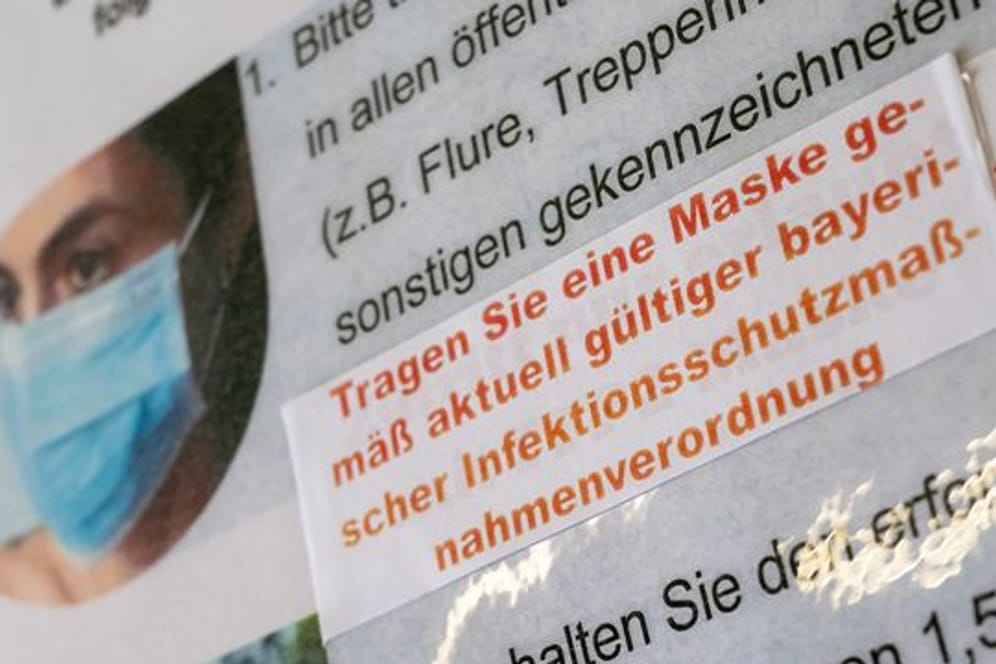 Ein Aufkleber mit der Aufschrift „Tragen Sie eine Maske gemäß aktuell gültiger bayerischer Infektionsschutzmaßnahmenverordnung“ ist an einem Hinweisschild im Amtsgericht in München zu sehen.