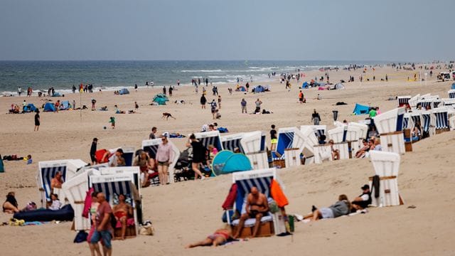 Besucher der Insel Sylt liegen in der strahlenden Sonne am Strand.