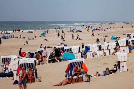 Besucher der Insel Sylt liegen in der strahlenden Sonne am Strand.