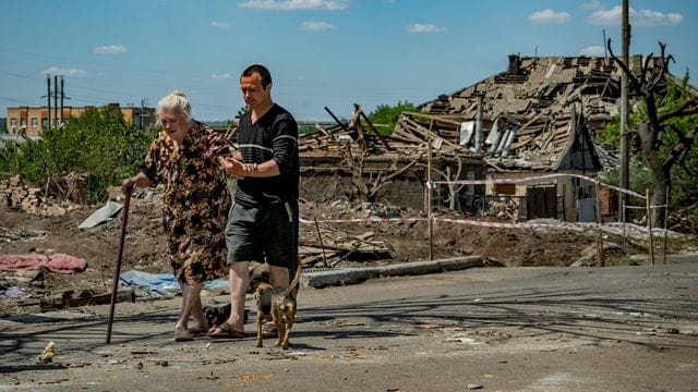 Eine alte Frau und ihr Sohn verlassen ihr zerstörtes Haus nach einem russischen Luftangriff auf die Stadt Druschkiwka in der Region Donezk.