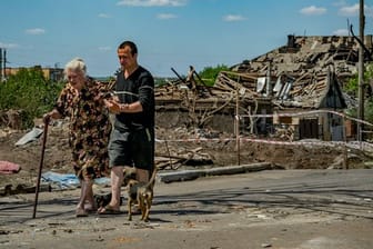 Eine alte Frau und ihr Sohn verlassen ihr zerstörtes Haus nach einem russischen Luftangriff auf die Stadt Druschkiwka in der Region Donezk.