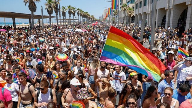 Teilnehmer schwenken Fahnen, Fächer und Schirme in Regenbogenfarben bei der Gay-Pride-Parade. Teilnehmer schwenken Fahnen, Fächer und Schirme in Regenbogenfarben bei der Gay-Pride-Parade.