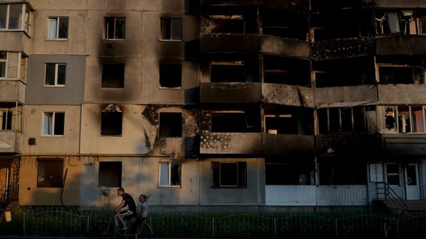 Ein Mann fährt mit dem Fahrrad vor einem zerstörten Gebäude in Borodjanka am Stadtrand von Kiew.