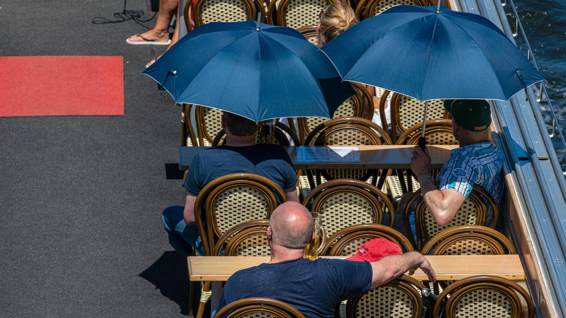 Menschen schützen sich mit Regenschirmen vor der Sonne: Hohe Temperaturen können das Herz-Kreislauf-System stark belasten.