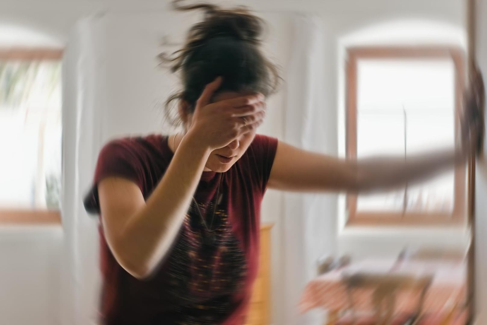 Eine Frau mit Schwindelattacke hält sich am Türrahmen fest.