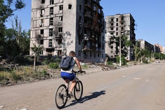Mann fährt durch das zerstörte Mariupol (Archivbild vom 10. Juni 2022)