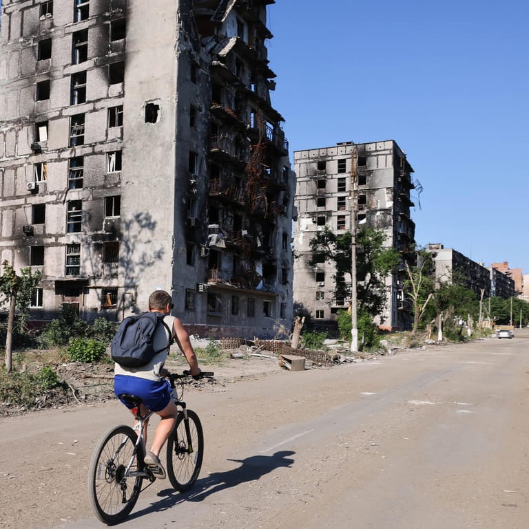 Mann fährt durch das zerstörte Mariupol (Archivbild vom 10. Juni 2022)