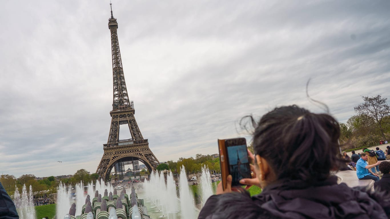 Eine Touristin vor dem Eiffelturm (Archivbild): Das Denkmal soll in einem schlechten Zustand sein.