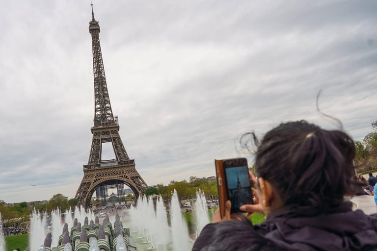 Eine Touristin vor dem Eiffelturm (Archivbild): Das Denkmal soll in einem schlechten Zustand sein.