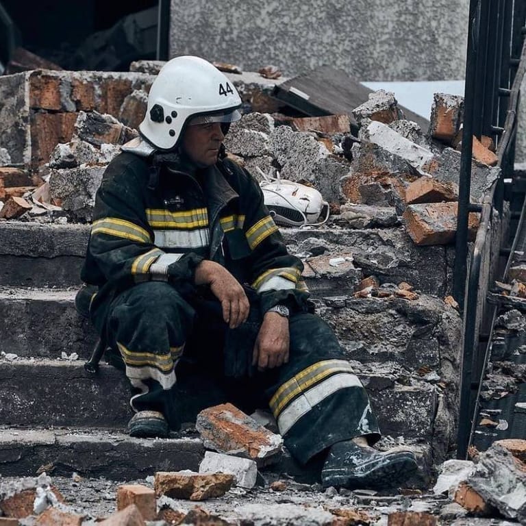 Feuerwehrmann vor einem zerstörten Haus in der Ukraine