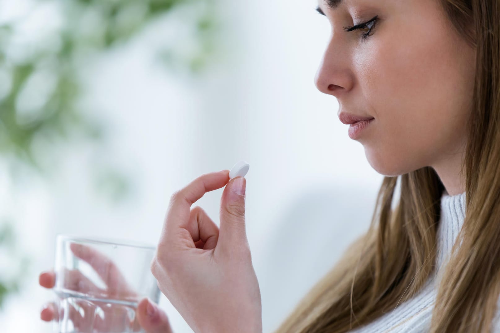 Frau hält Tablette und Wasserglas