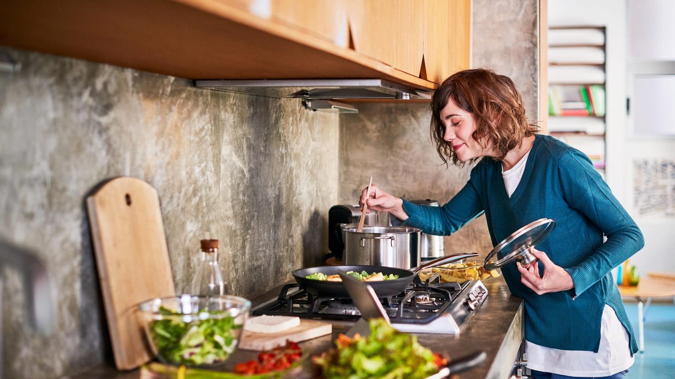 Frau beim Kochen gesunder Gerichte: Abnehmen kann mit leckeren Gerichten gelingen.