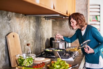 Frau beim Kochen gesunder Gerichte: Abnehmen kann mit leckeren Gerichten gelingen.