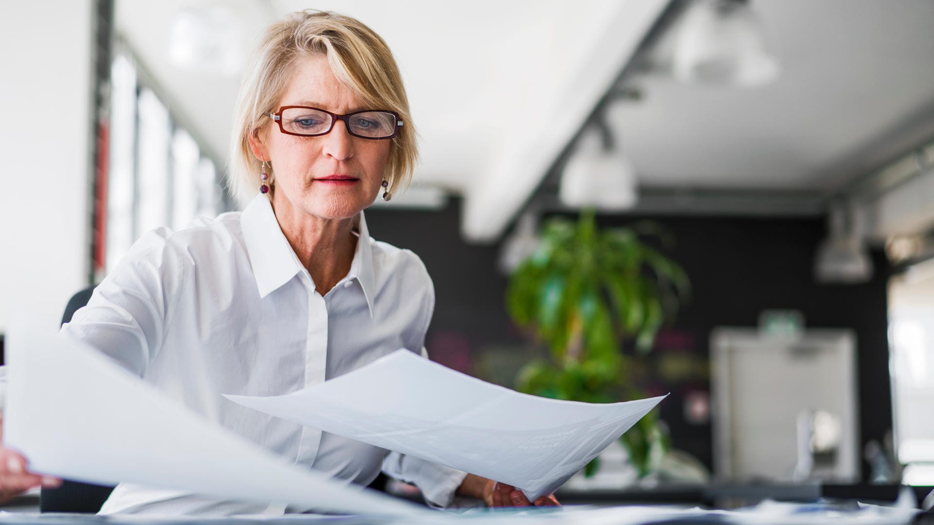 Eine Frau sichtet Unterlagen (Symbolbild): Wer mit dem Finanzamt kommunizieren will, benötigt in der Regel seine Steuernummer.