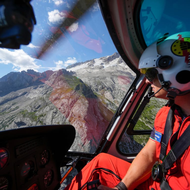 Ein Retter steuert einen Hubschrauber, um nach den Opfern der Gletscherlawine von Punta Rocca zu suchen: Fünf Menschen gelten noch als vermisst.