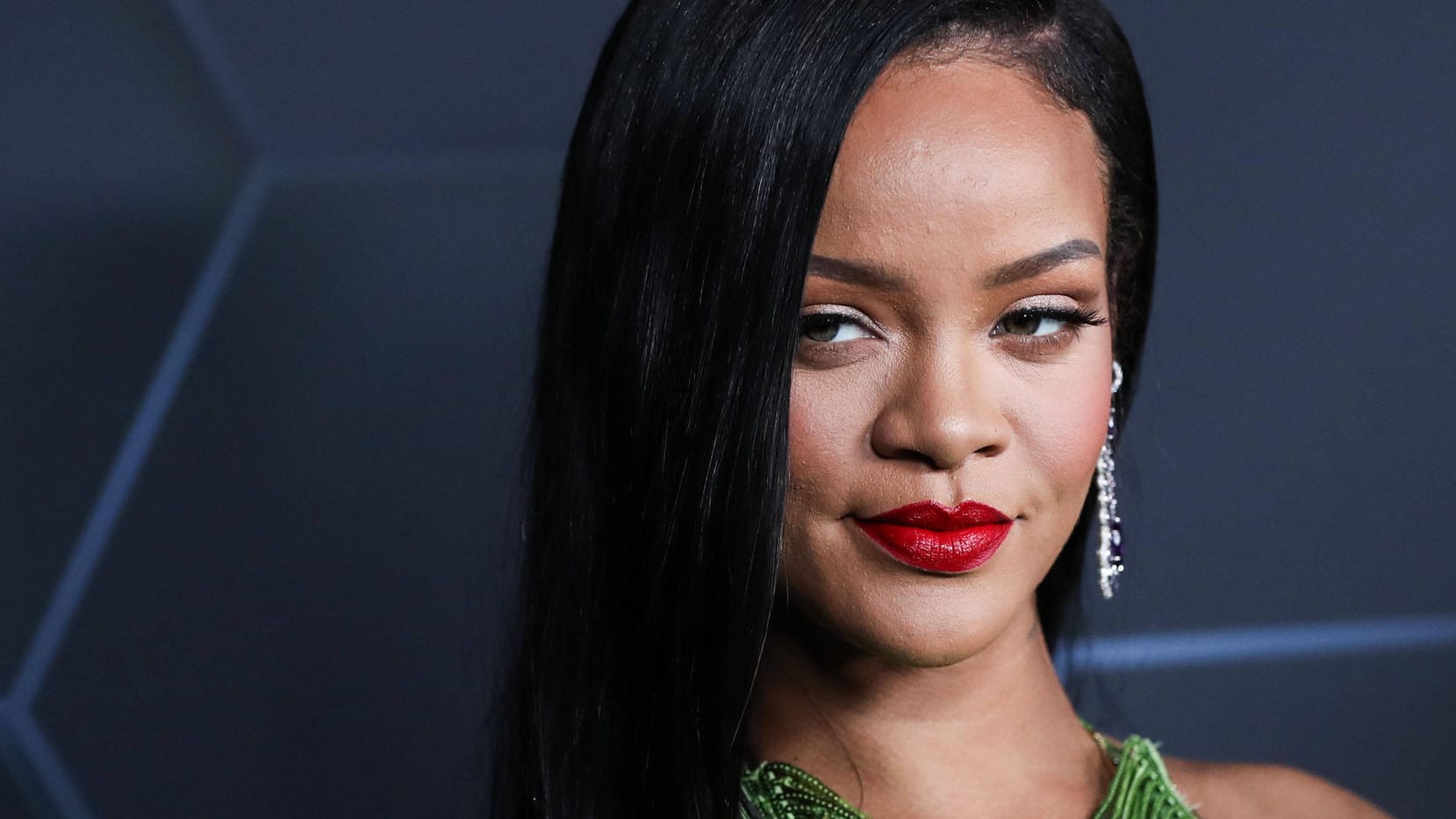 Rihanna posiert auf einem roten Teppich.