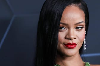 Rihanna posiert auf einem roten Teppich.