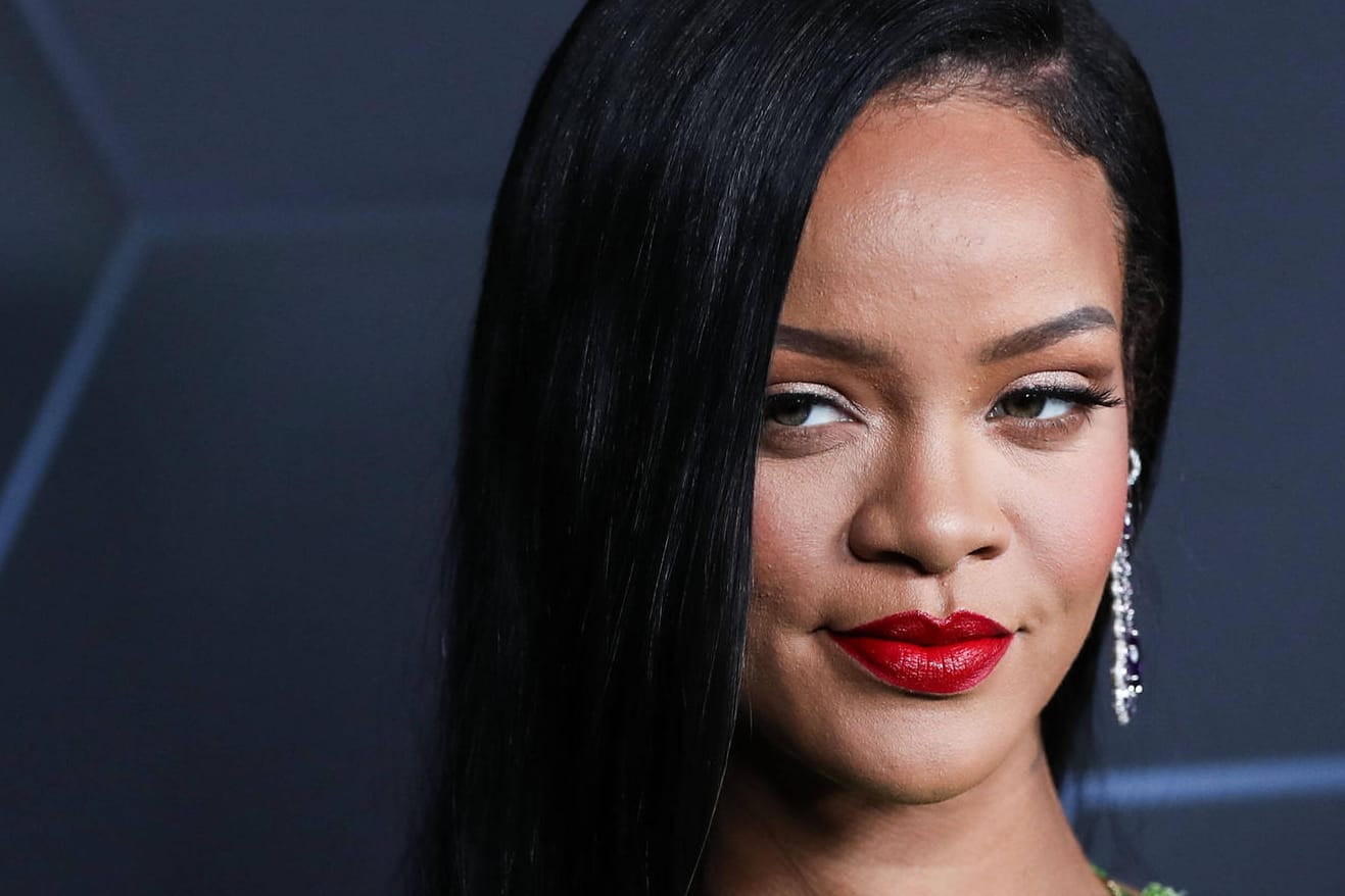 Rihanna posiert auf einem roten Teppich.