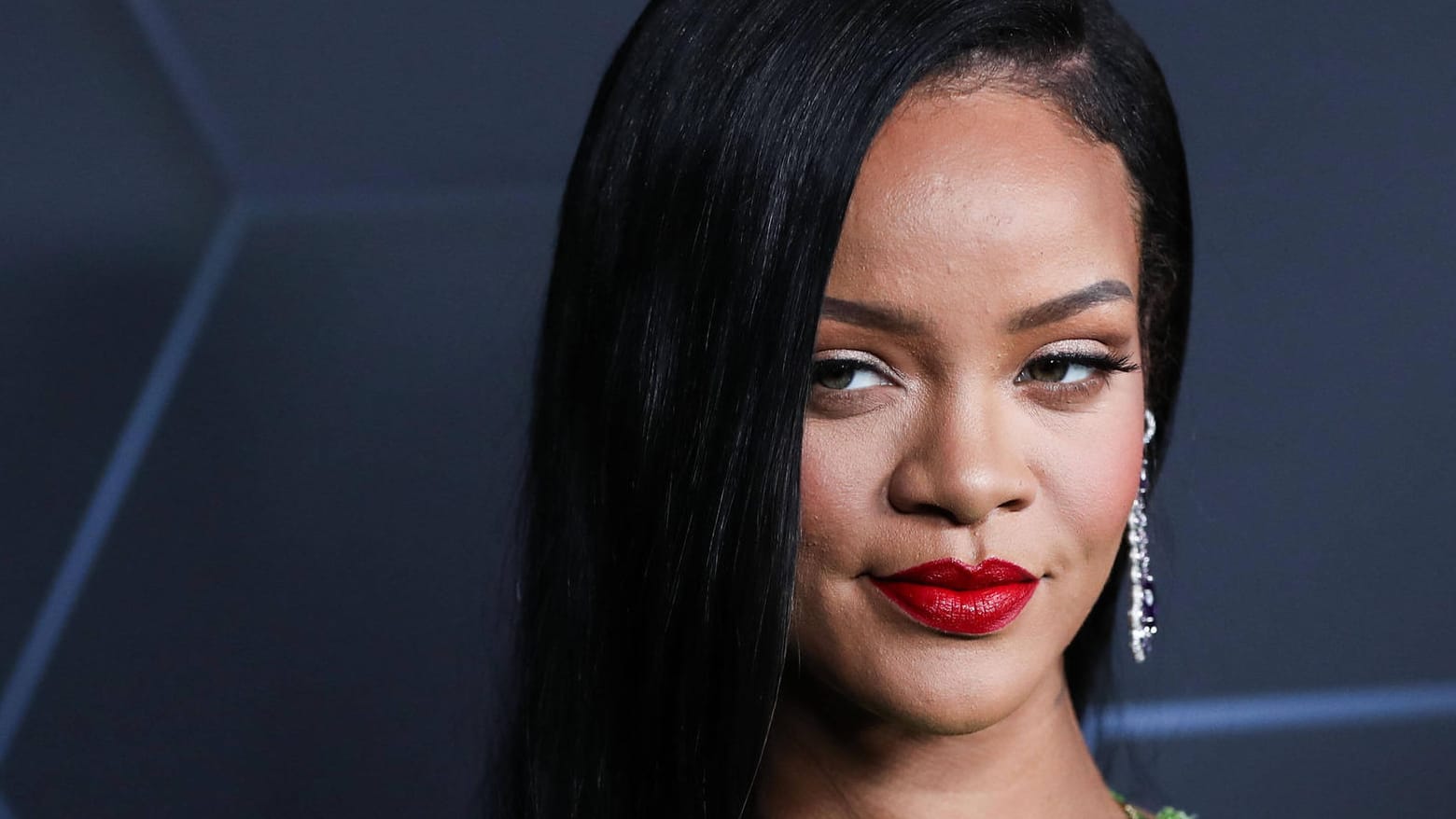 Rihanna posiert auf einem roten Teppich.