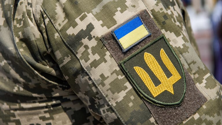 Das ukrainische Armeeabzeichen am Arm eines Soldaten (Archivbild): Die Ukraine sucht nach einem Abgeordneten, dem Hochverrat vorgeworfen wird.