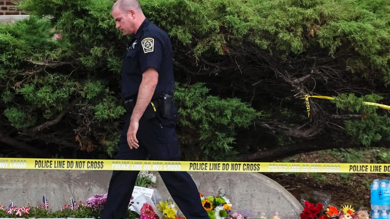 Ein Polizist geht an niedergelegte Blumen am Highland Park vorbei (Archivbild): Der festgenommene Mann soll eine weitere Tat geplant haben, so die Polizei.