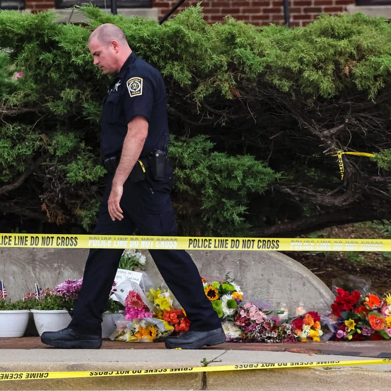 Ein Polizist geht an niedergelegte Blumen am Highland Park vorbei (Archivbild): Der festgenommene Mann soll eine weitere Tat geplant haben, so die Polizei.